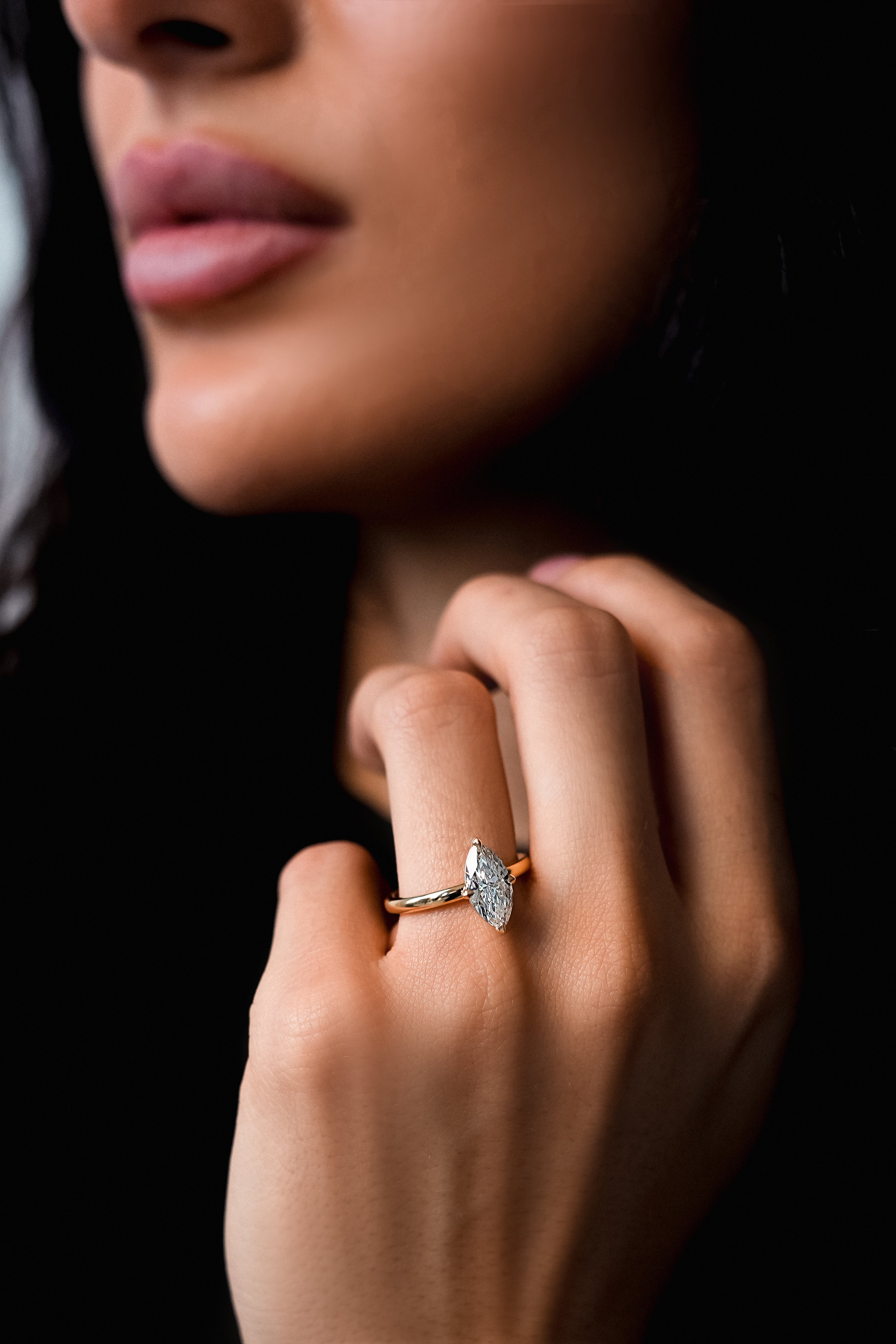 Close-up of a hand wearing a diamond ring with a dark background