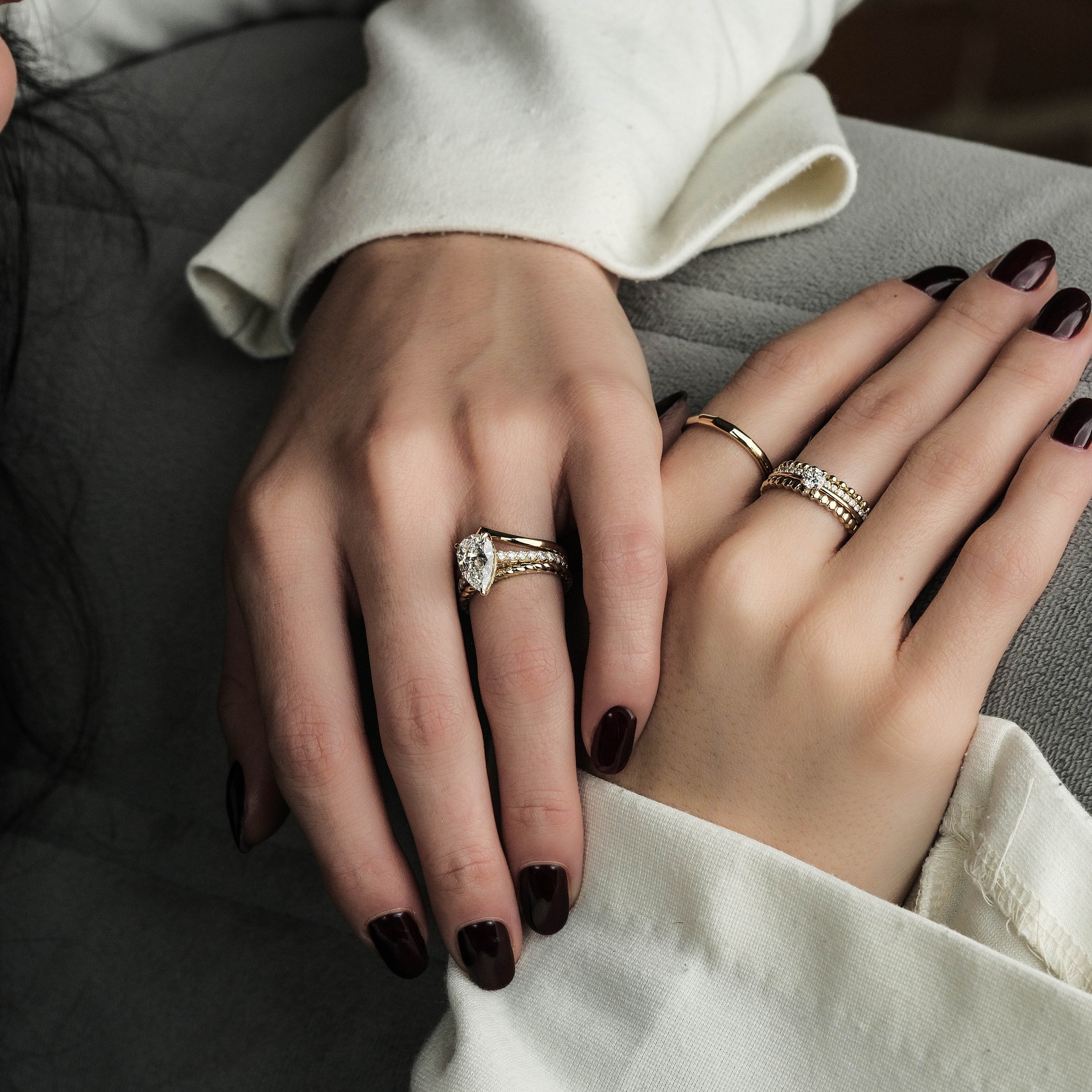 Close-up of two hands with rings, one wearing a white coat sleeve.