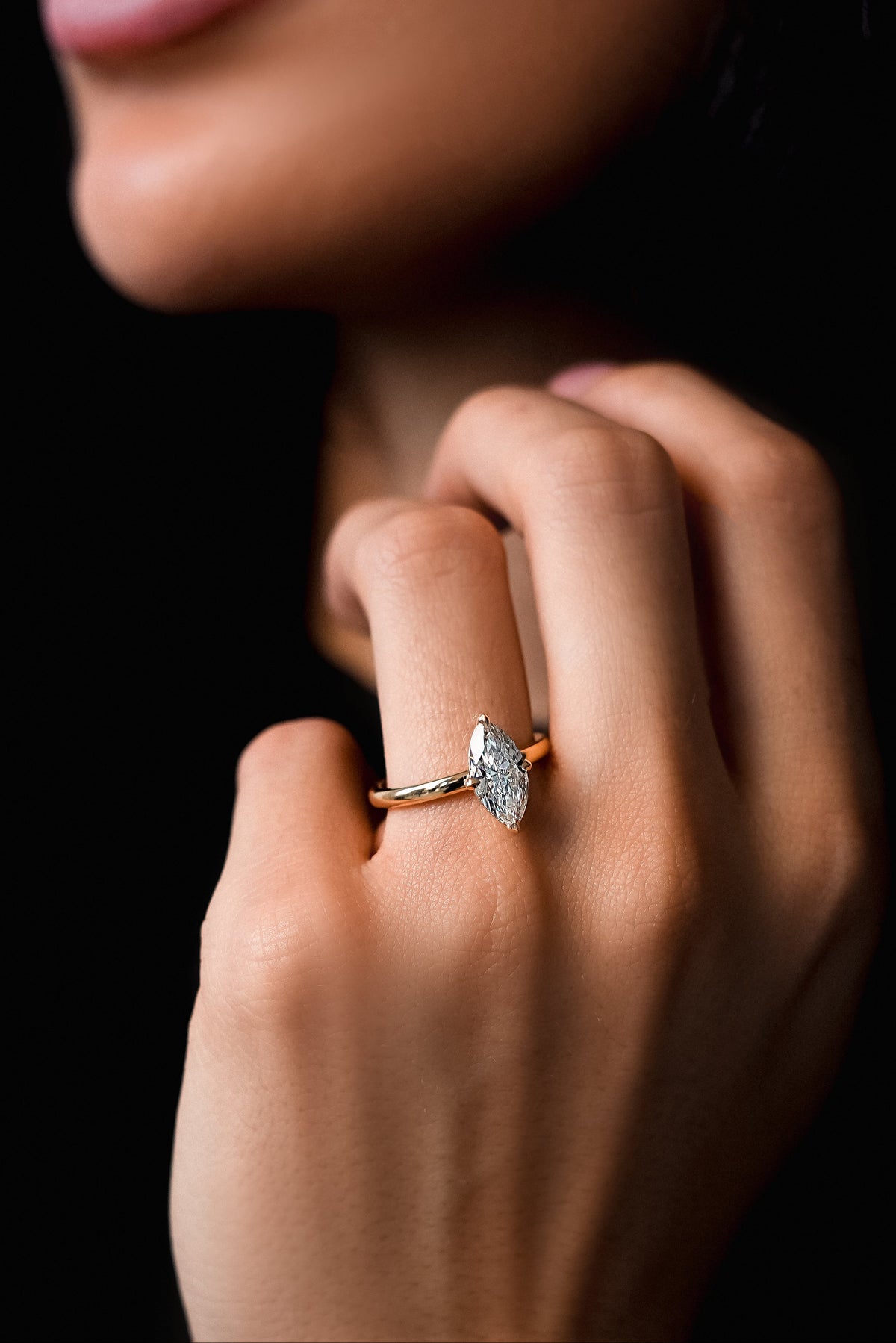Close-up of a hand wearing a diamond ring with a dark background