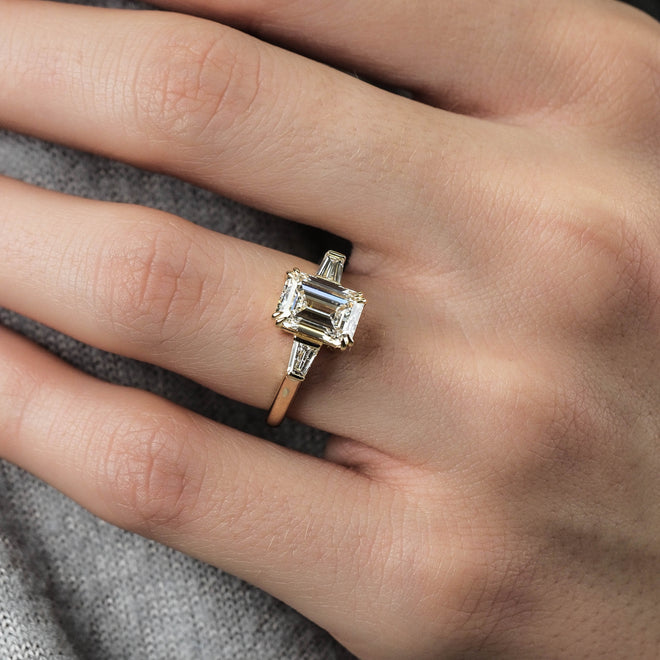Hand wearing a diamond ring on a gray fabric background