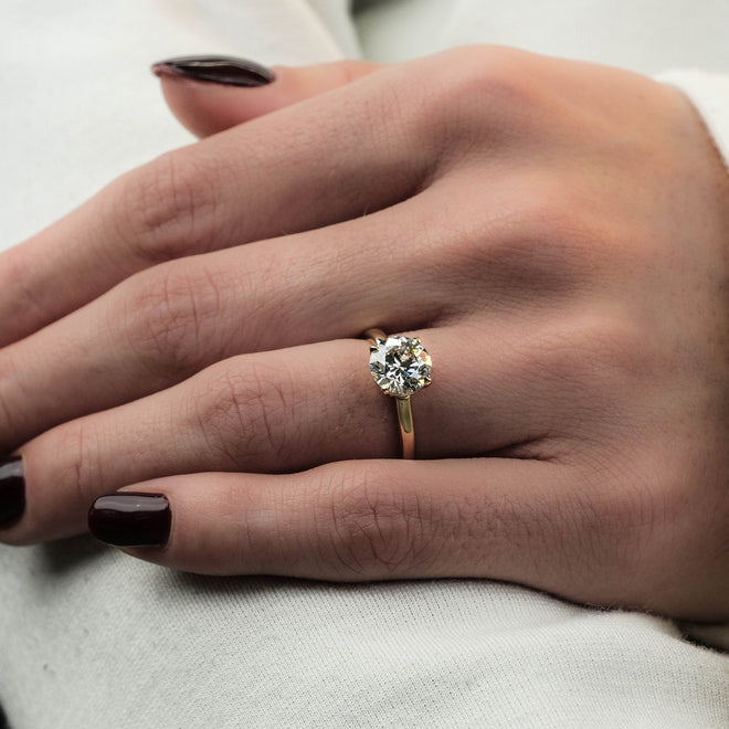 Hand wearing a diamond ring with a white background